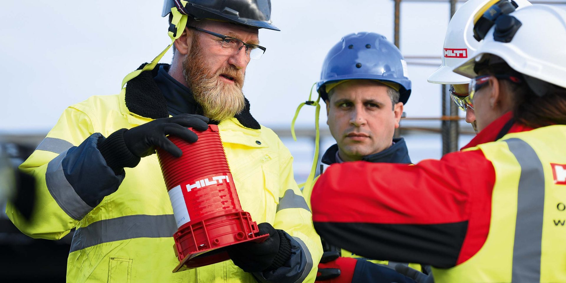 Bouwvakker en voorman of werfleider in gesprek, een Hilti brandbeveiligingsproduct van Hilti wordt in hun handen gehouden.