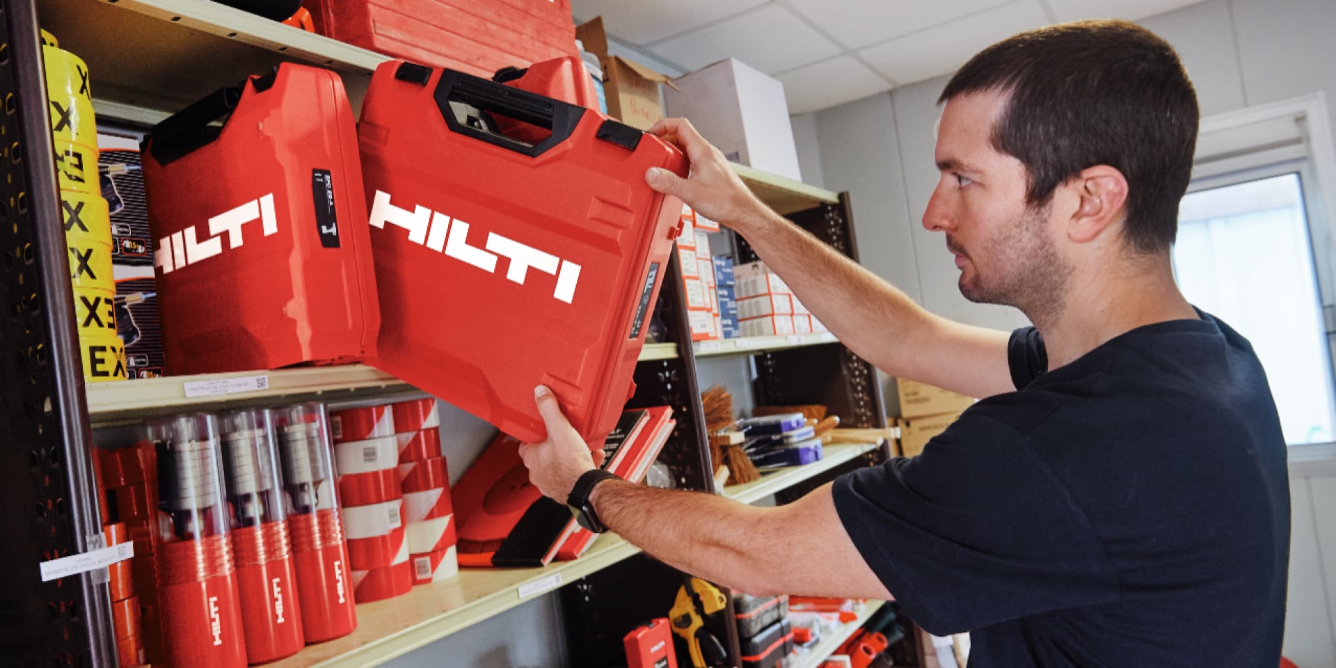 Osoba wsuwa walizkę Hilti na półkę.